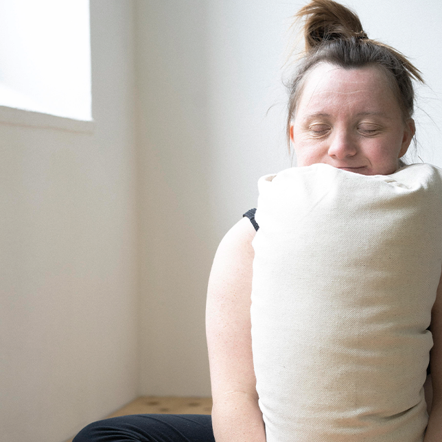 Eine Frau macht eine Yoga Übung auf dem hejhej-bolster und hat ihre Hände auf ihm