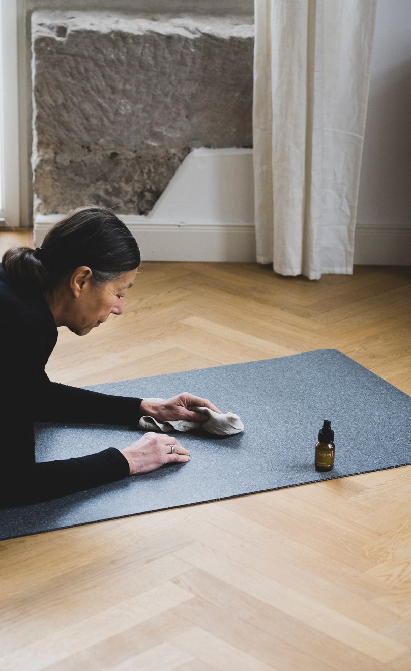 Eine Frau reinigt die dunkle hejhej-mat mit dem hejhej-spray