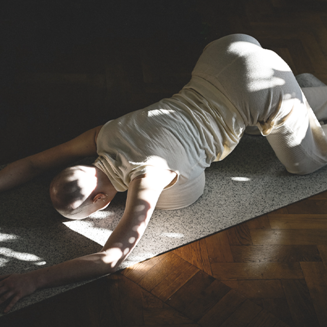 Eine Frau macht eine Yoga-Pose mit dem Meditationskissen in der Brust, um das Herz zu öffnen