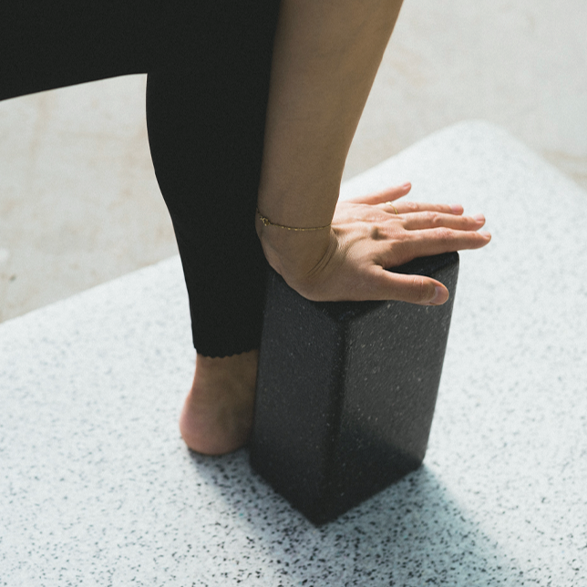 Eine Frau nahm eine Yoga-Haltung ein und benutzte den Block, der sie über der Hand stützte