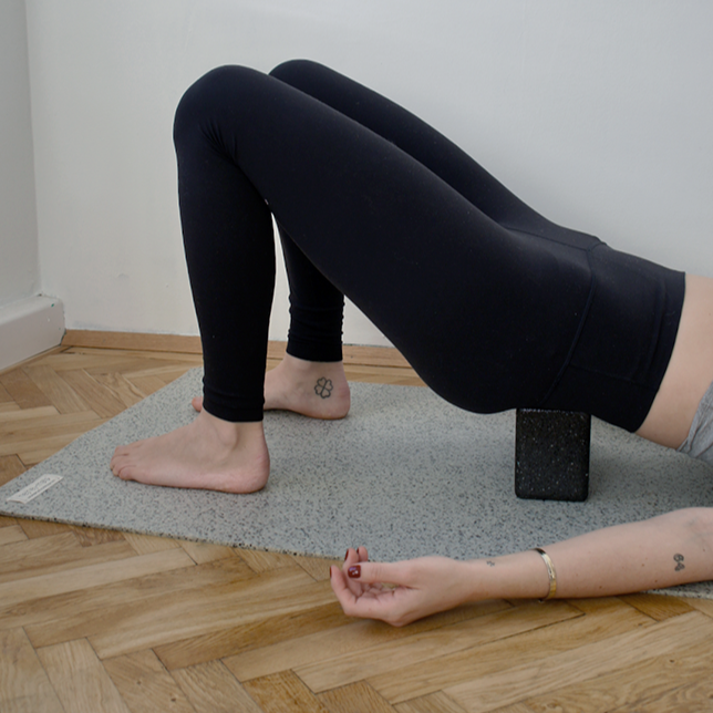 Eine Frau nahm eine Yoga-Haltung ein und benutzte den Block, um den Hintern zu stützen