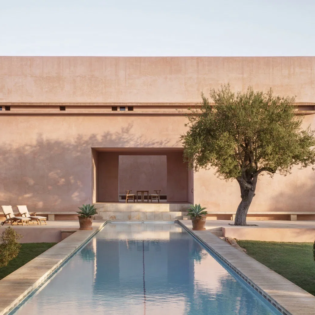 Ein toller länglicher Pool und am Ende steht ein wahnsinniges Haus das eine tolle Architektur hat und eine rosane Fassade