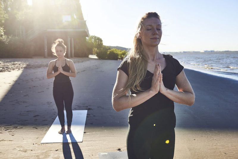 zwei junge Frauen beim Yoga - friedvolles Yoga als Teil von sozialem Yoga