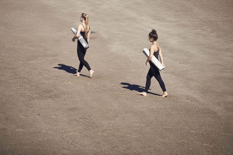 Zwei junge Frauen tragen ihre Yogamatte und zeigen, dass besonders die Kunden gefragt sind, um eine recycelbare Yogamatte zurückzuführen