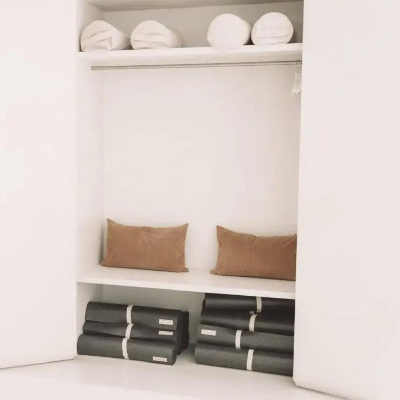 Die dunklen hejhej-mats und hejhej-bolster sind schön in einem weißen Schrank aufgewahrt