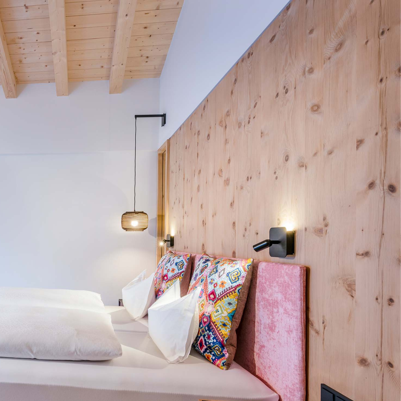 Ein aufgeräumtes Bett mit Holzwand dahinter