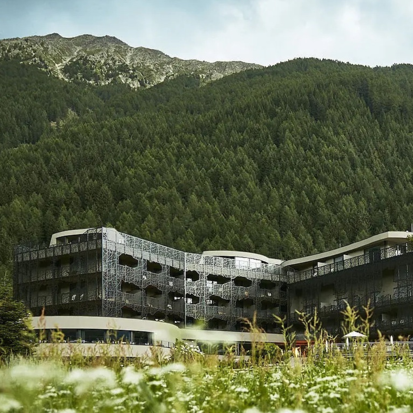 Super modernes Hotel mit einer architektonischen Fassade steht vor einem bewaldetem ᗑ