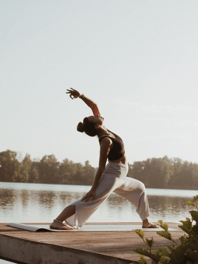 Junge Frau, die draußen Yoga macht und so ein ganzheitliches Körpergefühl ausstrahlt