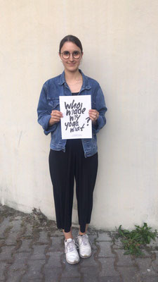 Viele Kunden, wie diese junge Frau fragen sich: Wer macht meine Yogamatte und halten ein Schild mit dieser Frage demonstrativ hoch