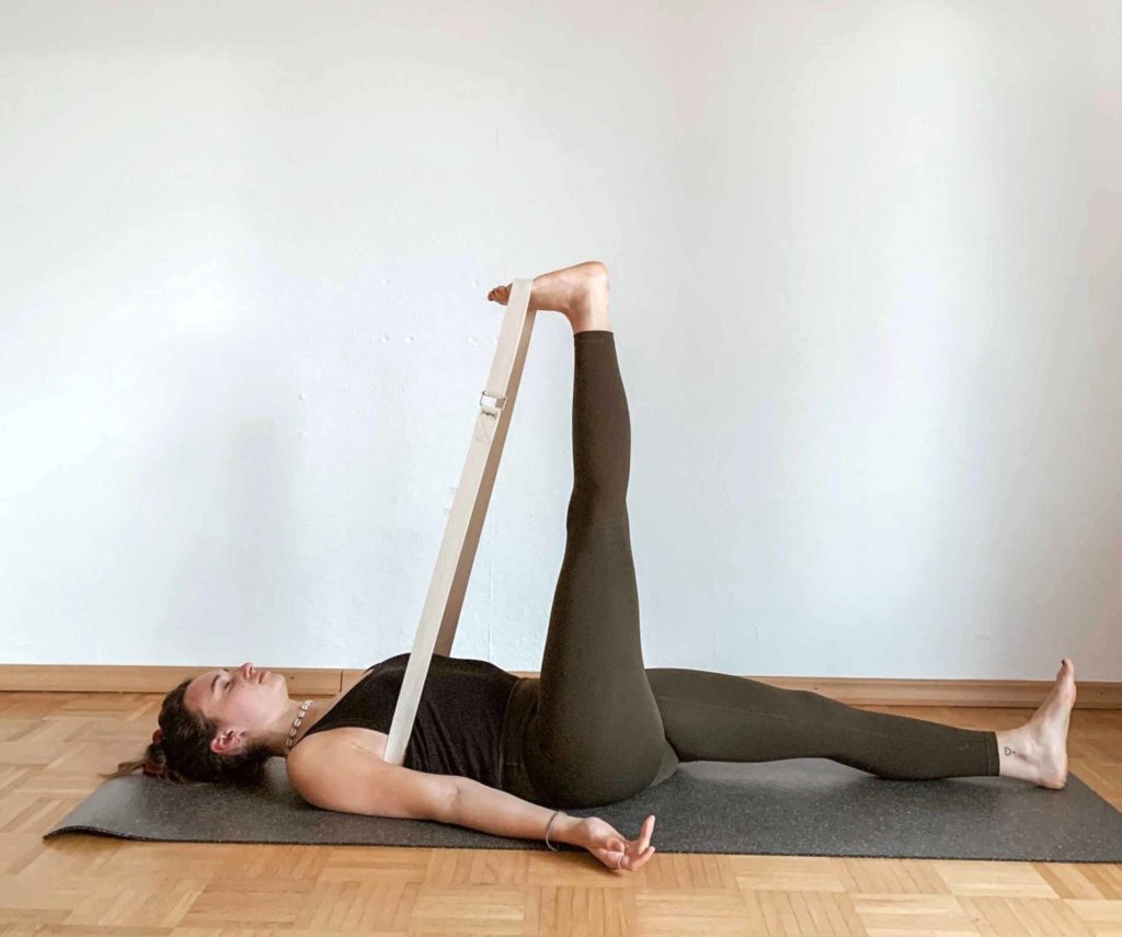 Nerina uses the yoga strap as a loop and has it between her chest and the ball of her feet, thus stretching the back of her legs