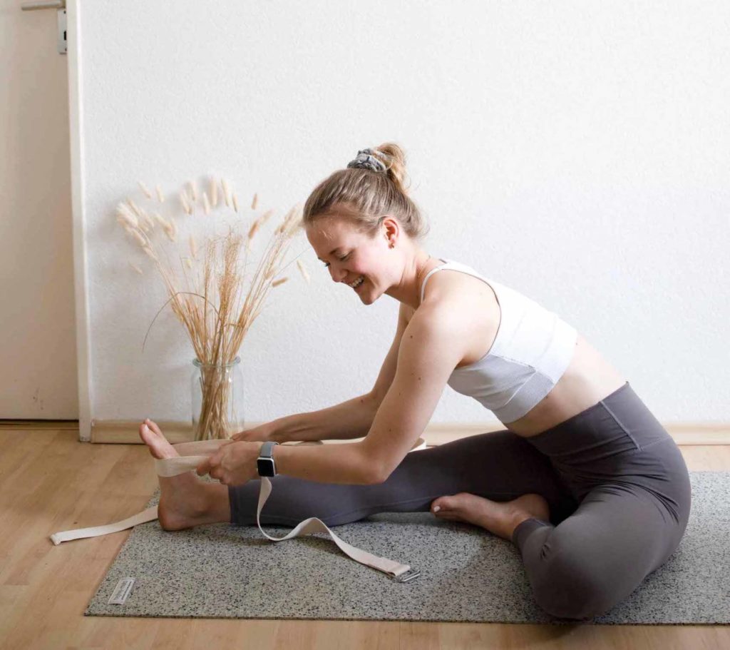 Sophia in the forward bend with the right leg, yoga strap serves as an extension of the arms