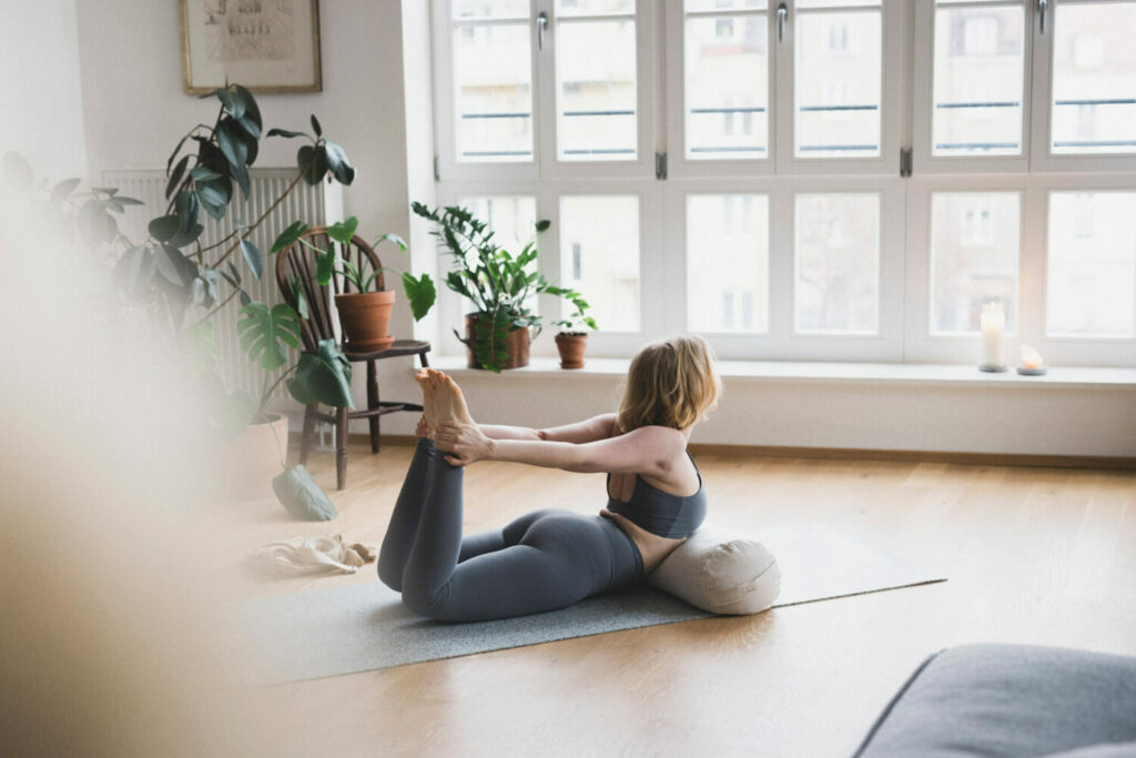 Blond girl in the yoga asana bow pose with the support of the hejhej-bolster