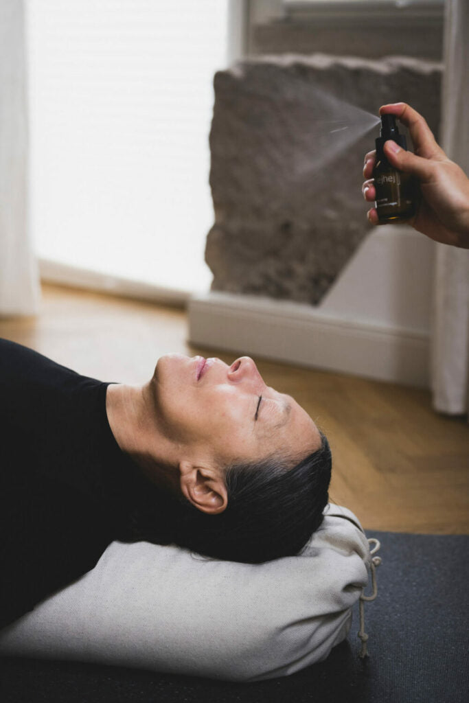 Das nachhaltige Yoga Spray würd über eine Frau zur Entspannung gesprüht.