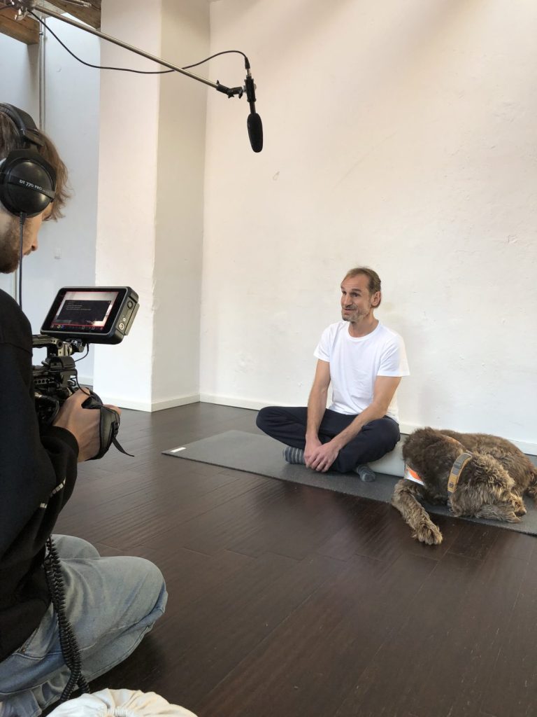 Hansi sits in front of the camera and his dog is right next to him