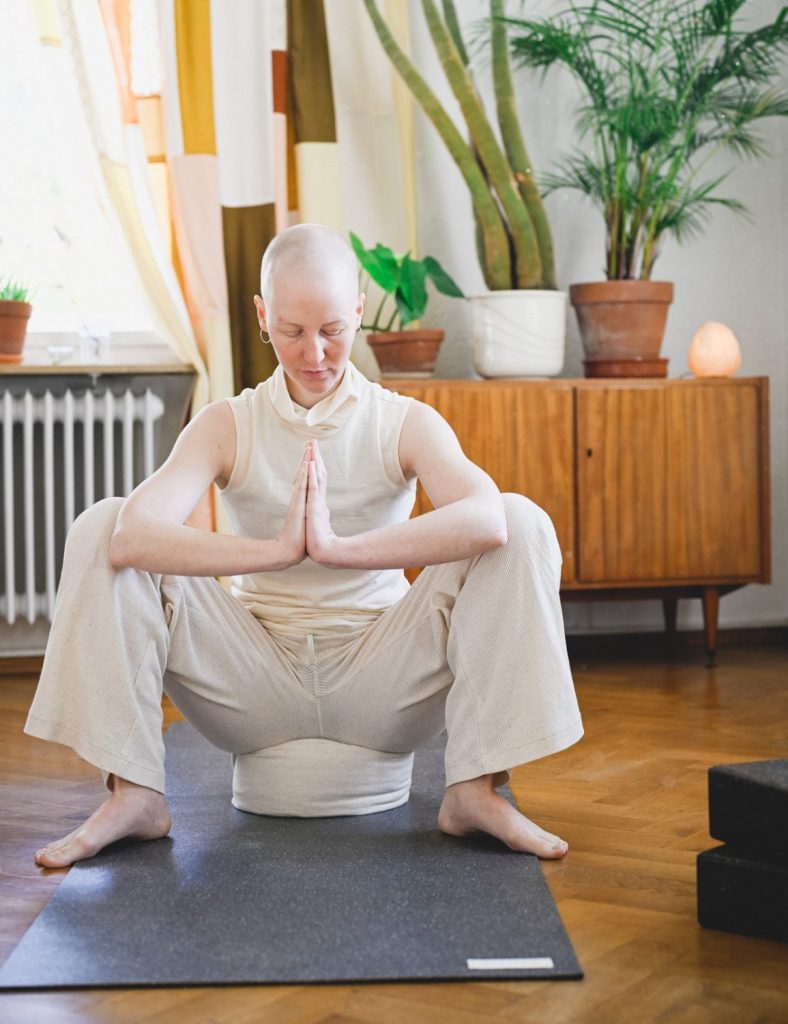 Yogi Squat auf dem hejhej-pillow mit Hönden in der Namaste Haltung
