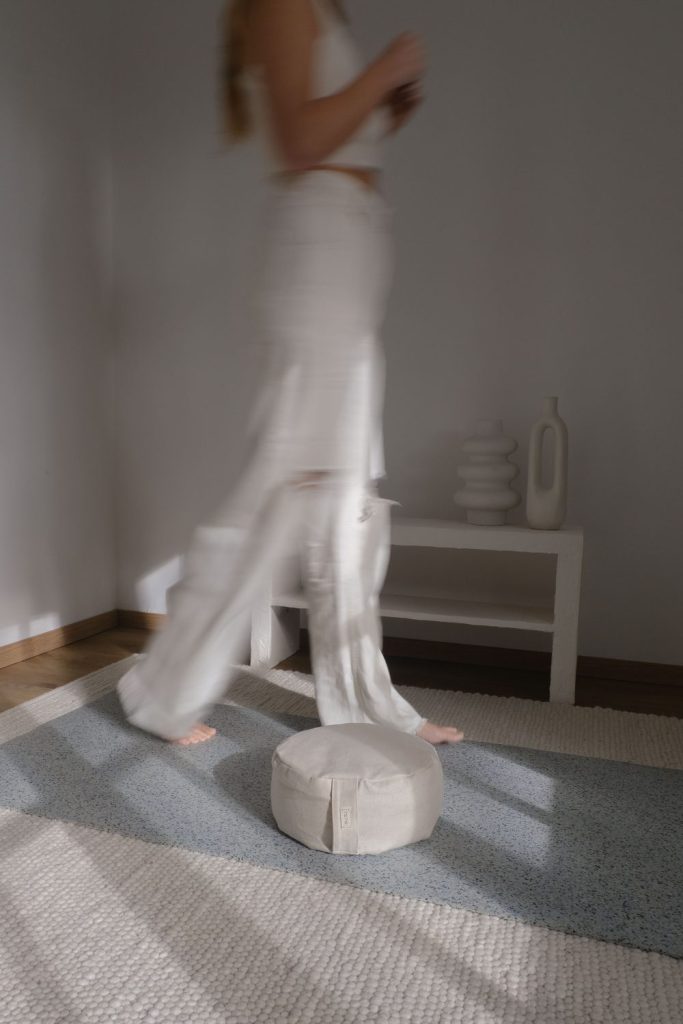 Eine Frau läuft auf der hejhej-mat und das Meditationskissen liegt daneben bereit für die Praxis