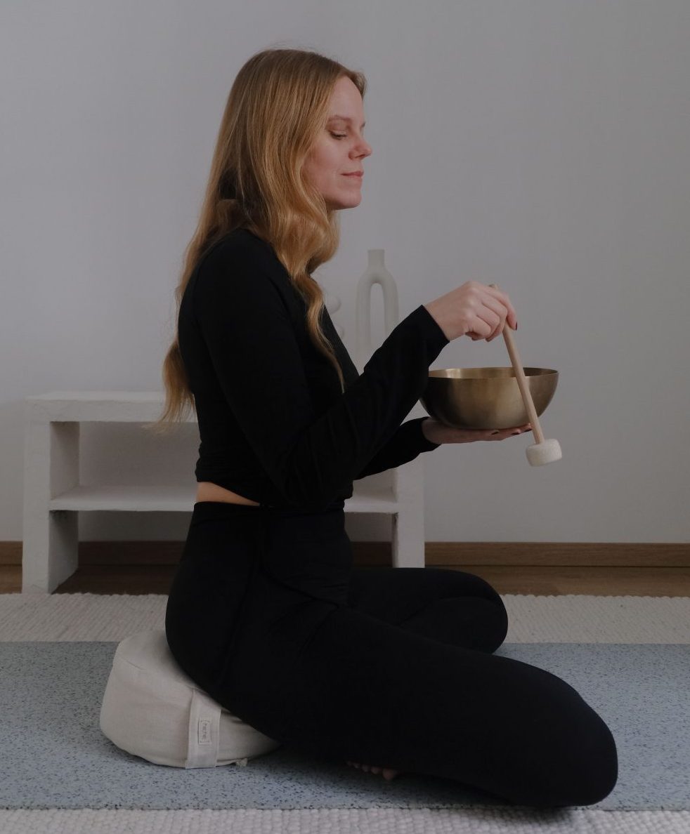 Yogalehrerin Nina sitzt auf dem hejhej-Kissen mit einer Klangschale.
